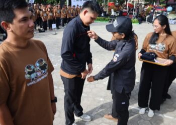 Hari Dermanto memasangkan jaket ke petugas yang akan mengawasi jalannya pilkada di Kukar