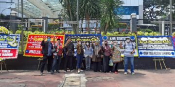 Protes para dosen dengan latar belakang karangan bunga yang berisi ujaran protes (foto: ADAKSI)