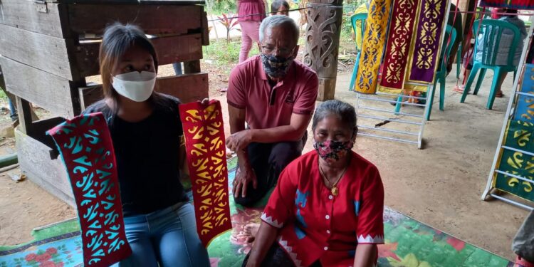 FE Lebiq, Sisilia Ramla, dan cucu mereka, memamerkan motif kriookng dalam pameran di Kampung Linggang Melapeh pada akhir 2021 (foto: Nofiyatul Chalimah)
