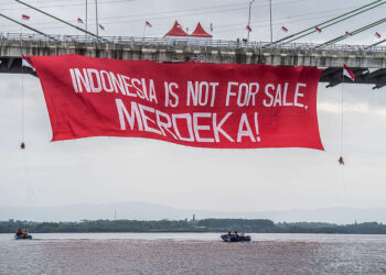 Aktivis Greenpeace membentangkan banner saat aksi damai kreatif di Jembatan Pulau Balang, Kalimantan Timur