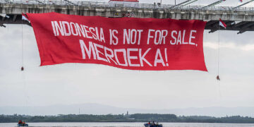 Aktivis Greenpeace membentangkan banner saat aksi damai kreatif di Jembatan Pulau Balang, Kalimantan Timur